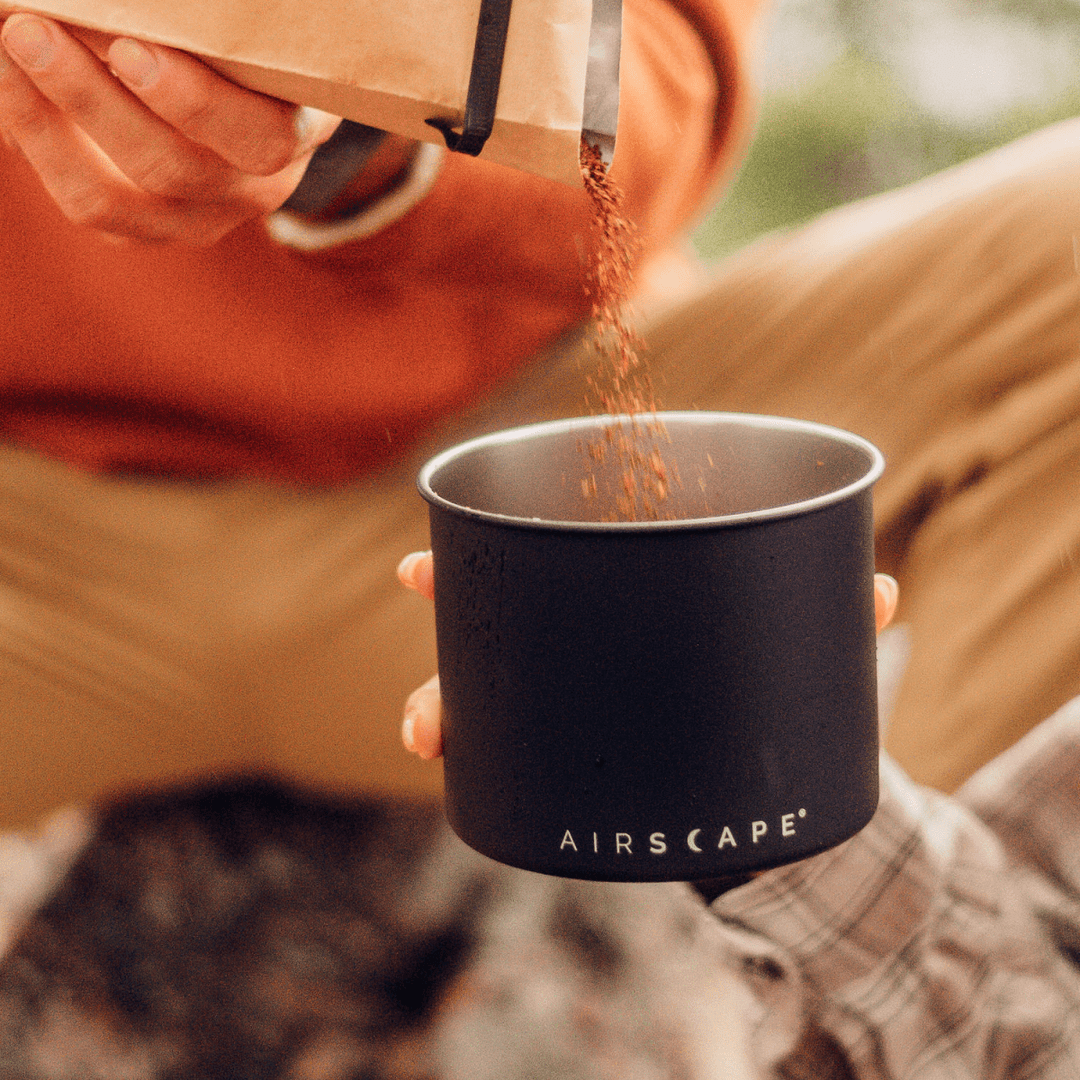 Friskmalet kaffe hældes i den mat sorte Airscape dåse